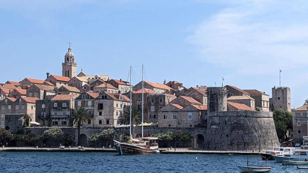 A cluster of buildings with red roofs as seen from the sea. With fortifications along part of the sea front.