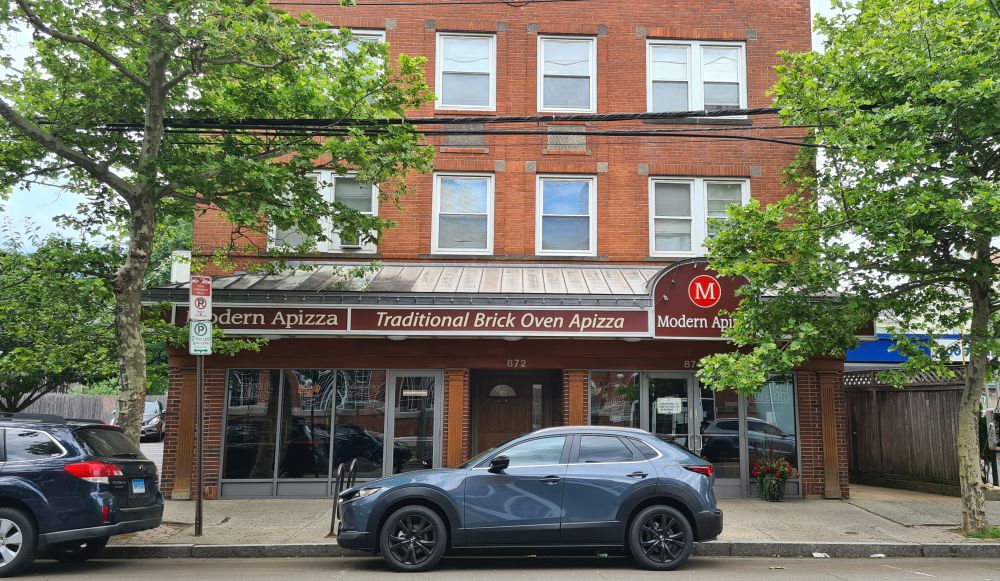 Brick building with the Modern pizza in the storefront on the ground floor.