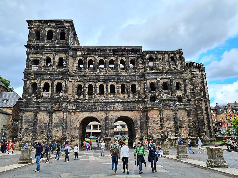 A four-story stone building, stained black, with arched gateway and many arched windows.