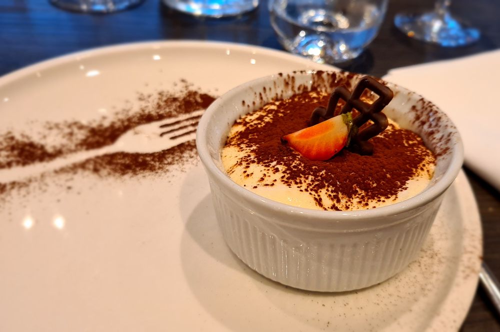 A dessert in a small dish sprinkled with cocoa powder.