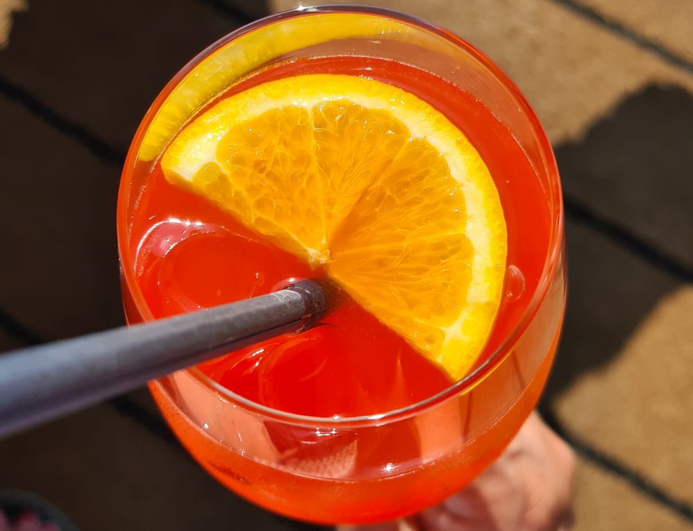 A bright pink drink with a orange slice.