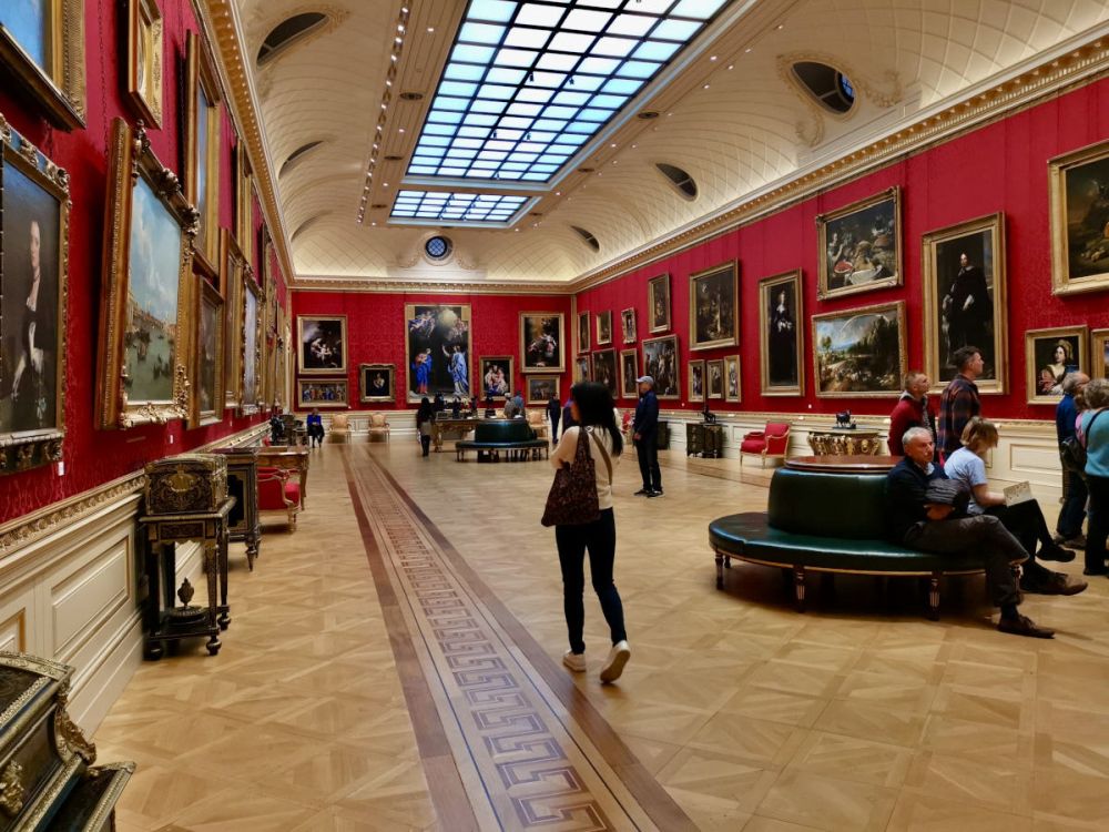 A long rectangular room, the walls lined with paintings.