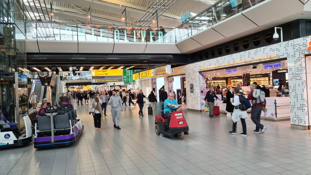 A large hall, shops visible, people walking up or down the hall.