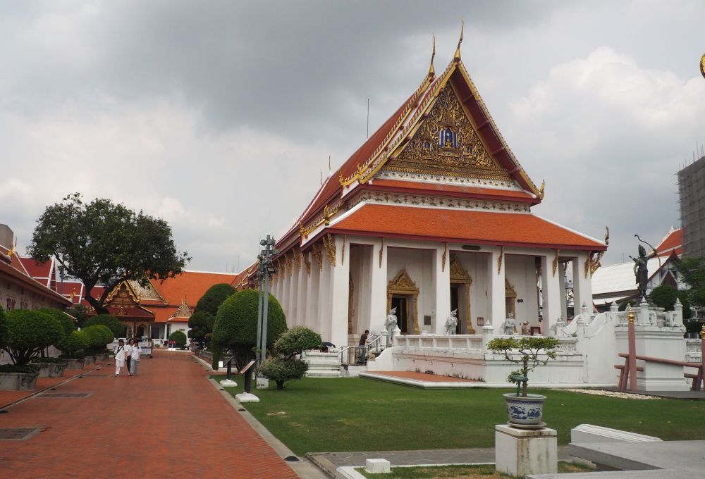 Typical Thai temple architecture: red roof with eaves extending beyond the white building, pillars across the front.