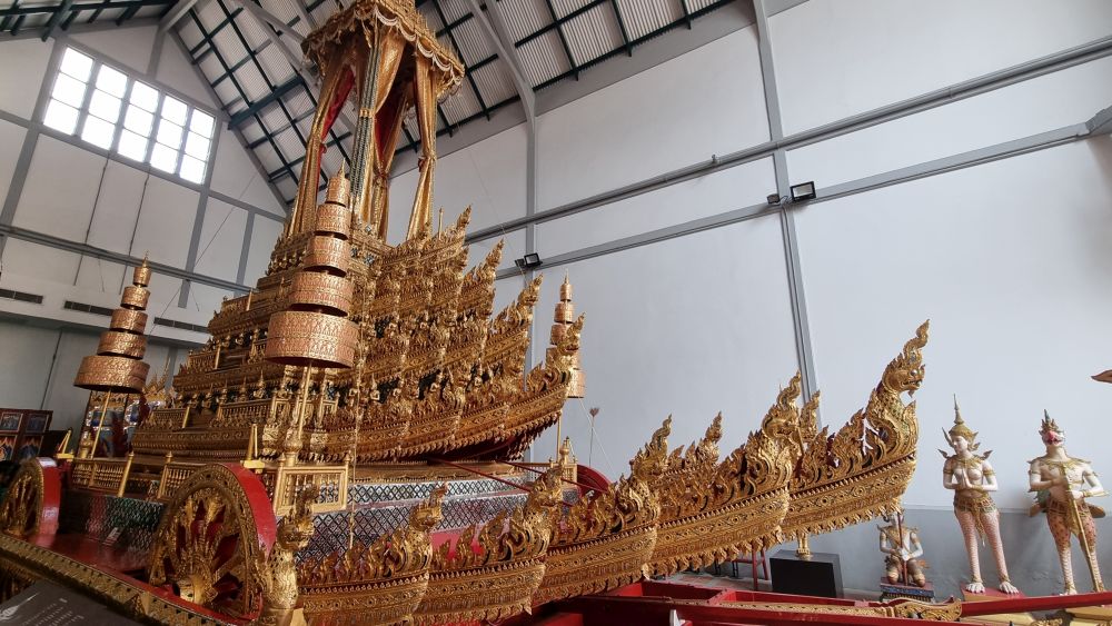 In a large hall, a gold-painted chariot with many carved details.