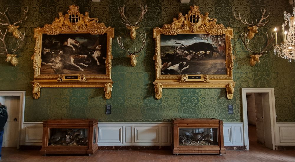 Two paintings of dogs hunting, each with an ornate gold frame.