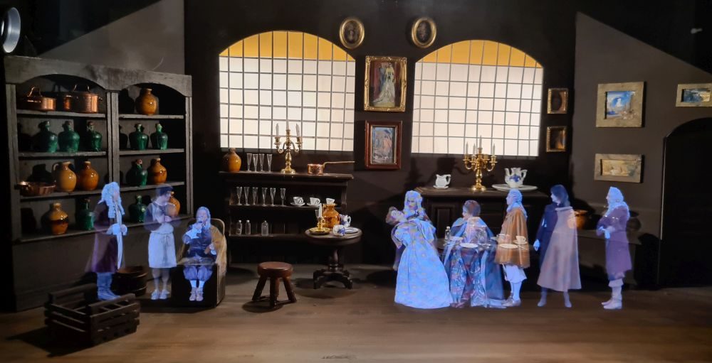 Inside a dollhouse image of a Renaissance-era room, people in period costume wait to try wine.