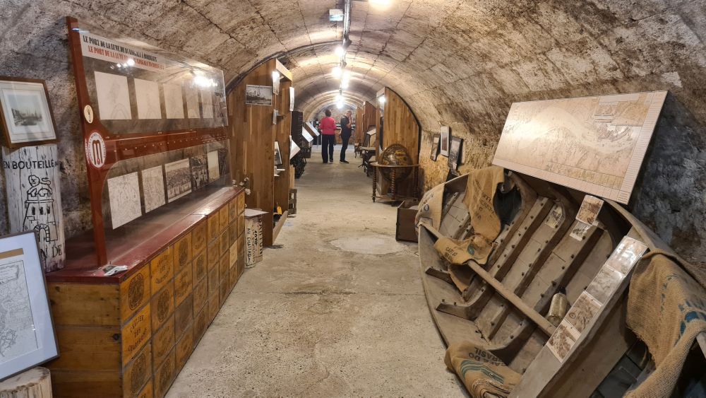 A long stone arched space, with a small boat leaning on the right and a cabinet on the left.