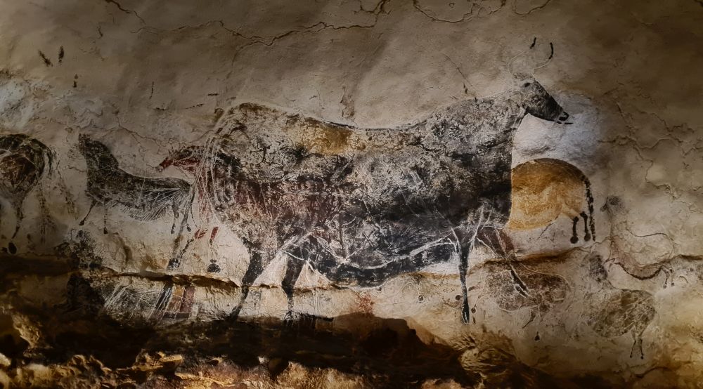 A black bull with other smaller animals behind it, creating a sense of perspective.