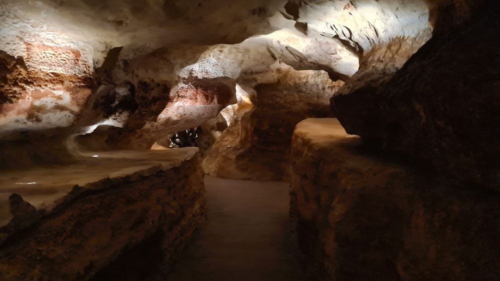 A flat walking surface, but then the walls on either side and the ceiling are rough and craggy.