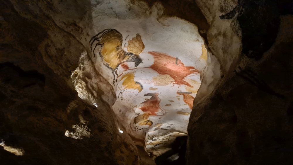 A view along the cave, where images of animals are visible on the ceiling.