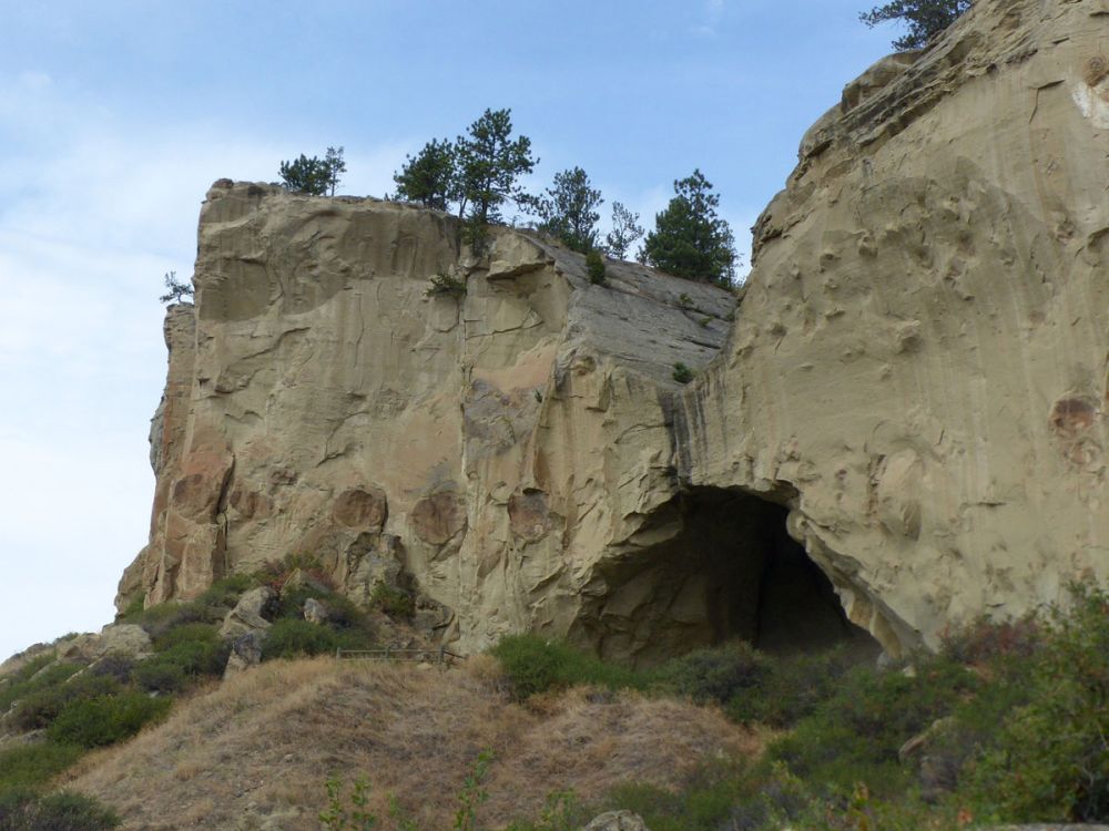 The cave entrance at the base of a cliff.