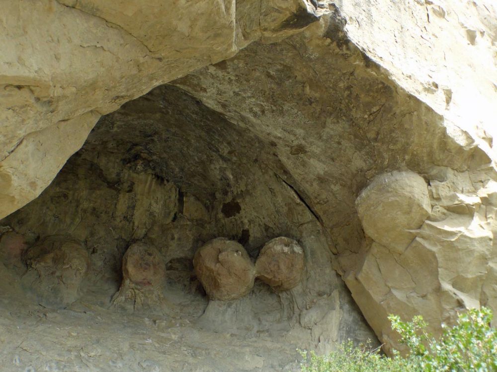 A cave with, along the visible part of the interior, ball shapes emerging from the rock.