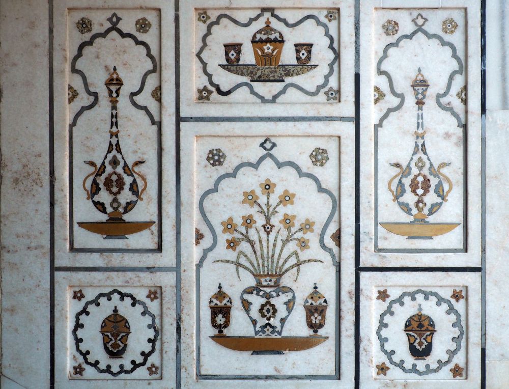 Inlaid artwork on marble shows vases of flowers and other vessels.