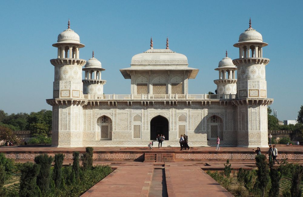 A white marble building with a square raised section in the center and a tower on each corner.