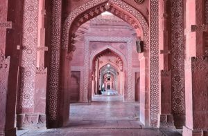 A long view down a series of ornately-decorated red sandstone arches.