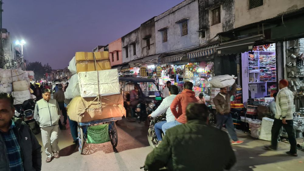 A busy street with carts piled high with goods; also motorcycles and pedestrians.