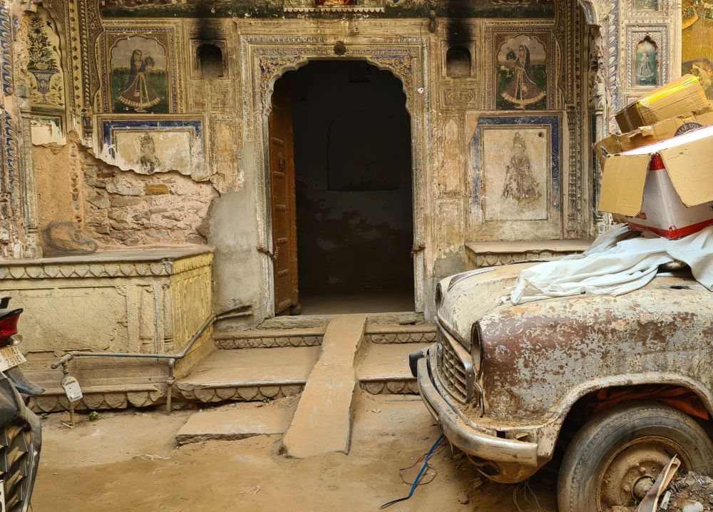 An archway with very faded and damaged paintings around it.