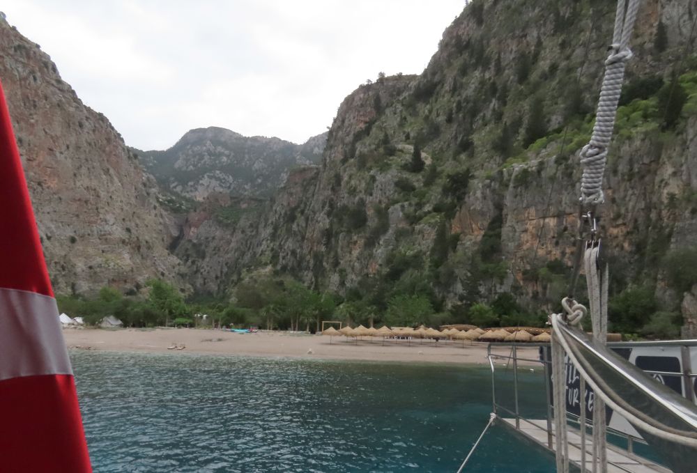 A small beach with rows of umbrellas, all edged by high cliffs.