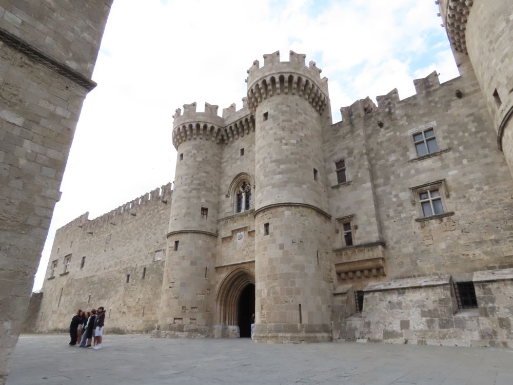 A castle with an arched entrance flanked by round stone towers, crenellated on top.