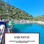 Text: Sailnstay: A review of a weeklong cruise along the Turkish coast. Image: a view of a cove and calm blue water seen along the side of the boat.