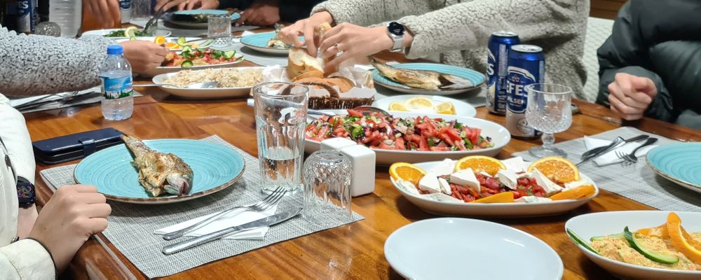 People serve themselves from a row of platters down the center of the table.