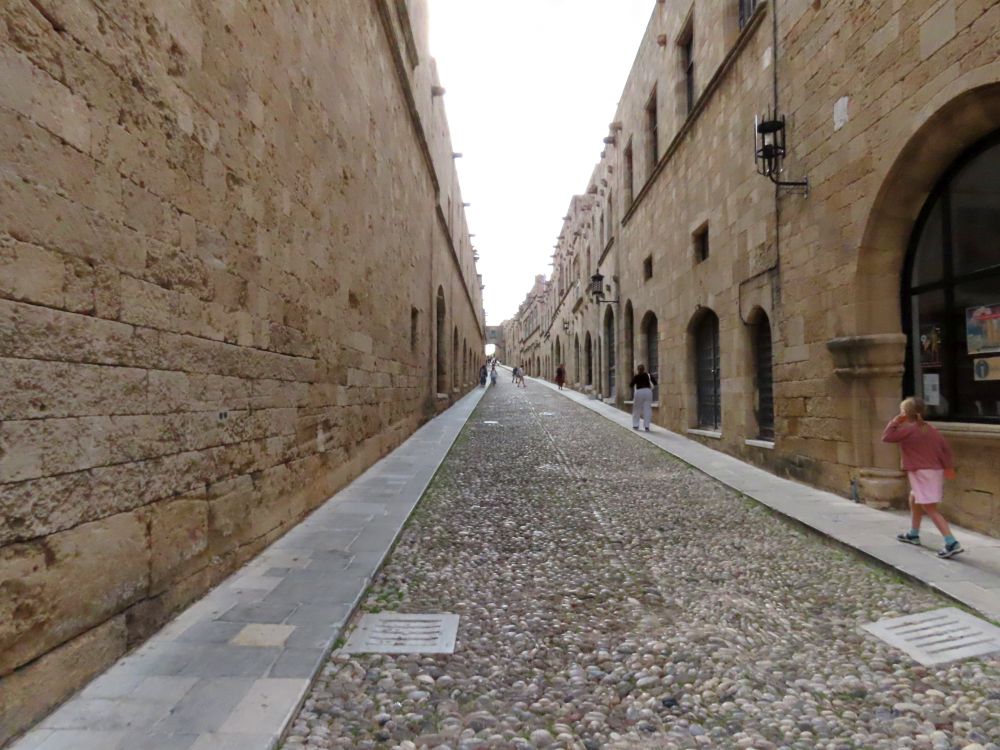 Looking up a cobbled street lined with stone buildings.