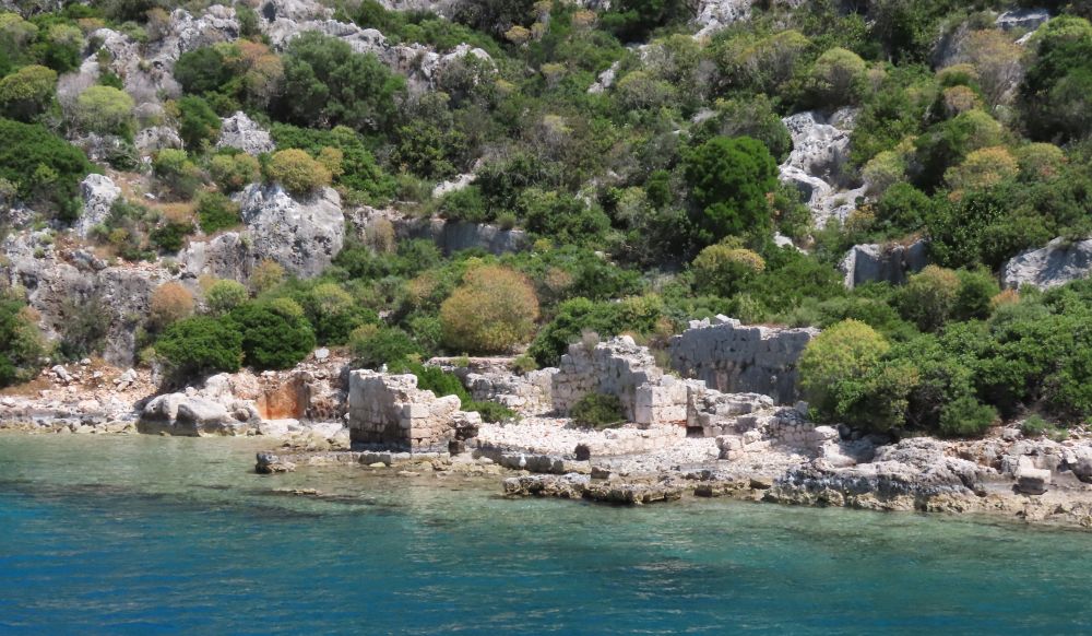 A few ruined buildings right on the edge of the water, some foundations visible in the water.