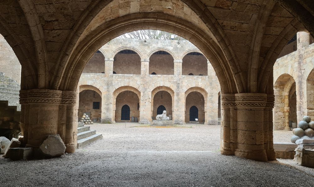 A rounded archway looks into an open courtyard with two arched stories across the way.
