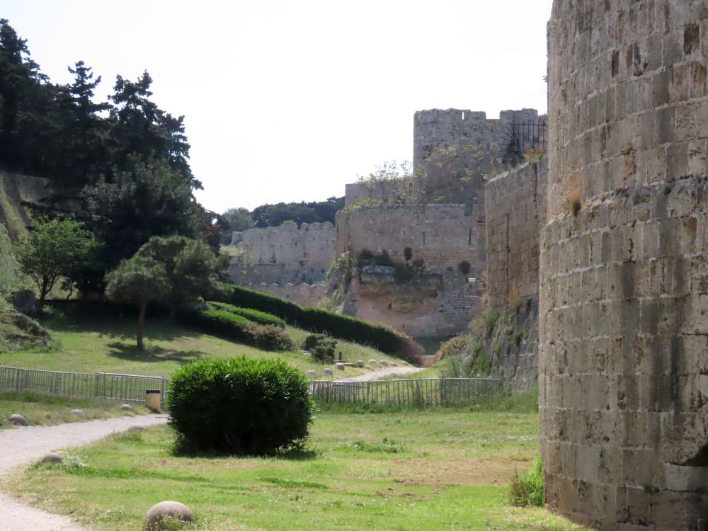 The park-like dry moat, with high fortress walls on one side and an embankment on the other.