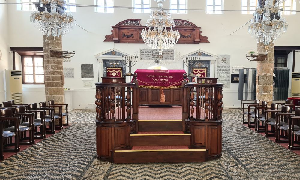 platform in the center of the room for torah reading; stone mosaic floor; chairs on the left and right.