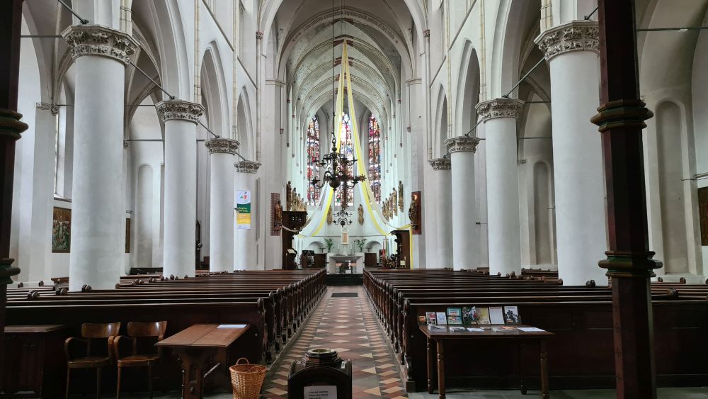 A church interior, looking toward the altar: white columns along the sides, arches between them, arched roof.
