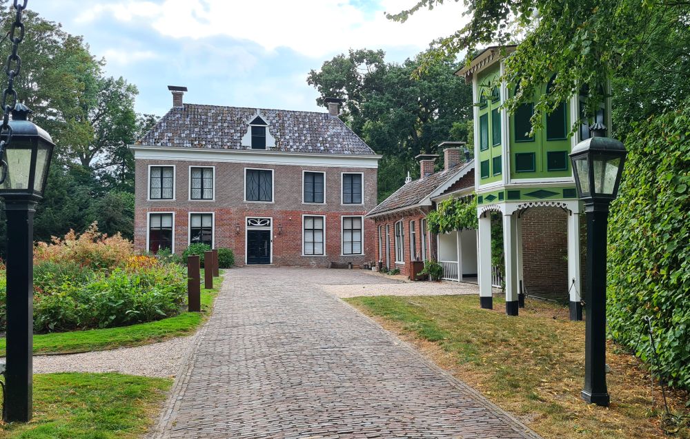 Looking down a straight gravel drive to an elegant brick house.