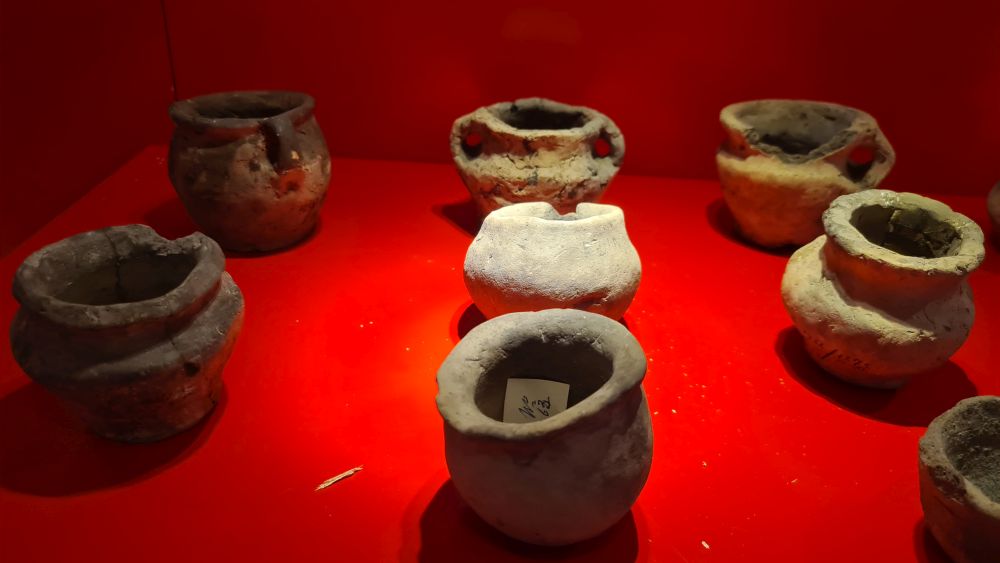 A group of quite primitive round pots on a red background.