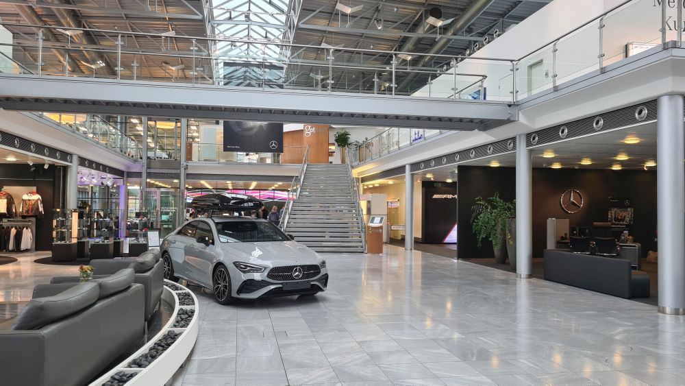 A large, high-roofed space, with a walkway across above it, and a car parked on a shiny floor.