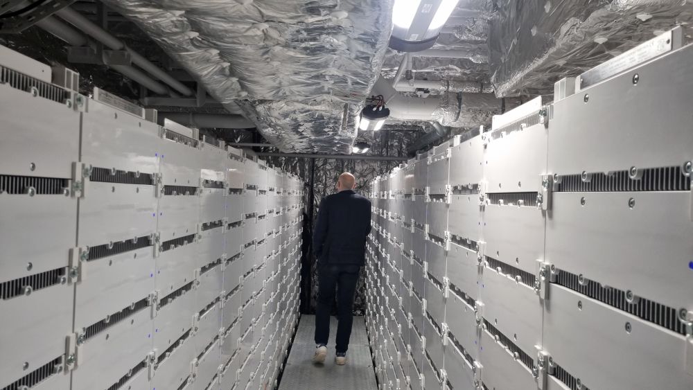 Long narrow aisle between white walls of batteries, with a low, foil-lined ceiling.