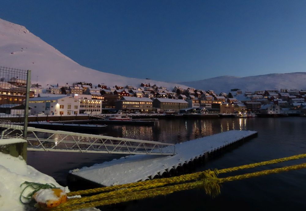 Looking across a bay at a cluster of houses in a bluish light.