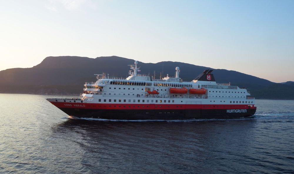 The ship in the livery of Hurtigruten: black hull, red strip above that, and white above that.