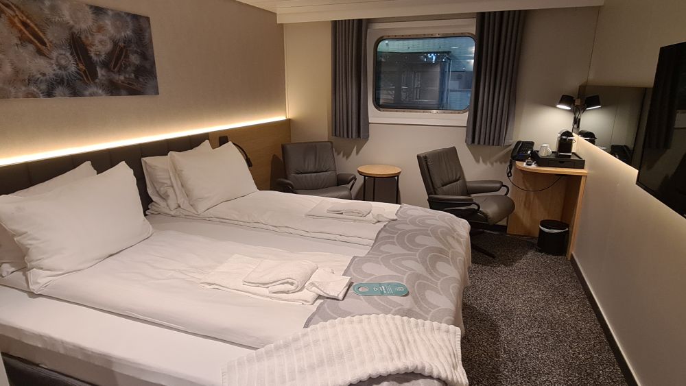 Bed on the left, with chairs under the window on the background.