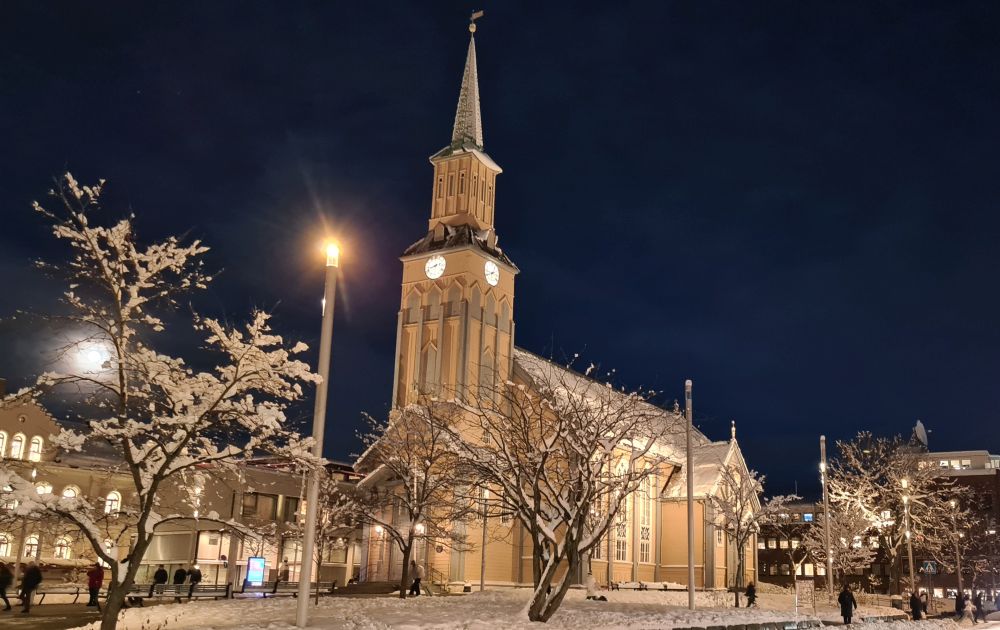 A quintessential church with snow-dusted trees in front of it.