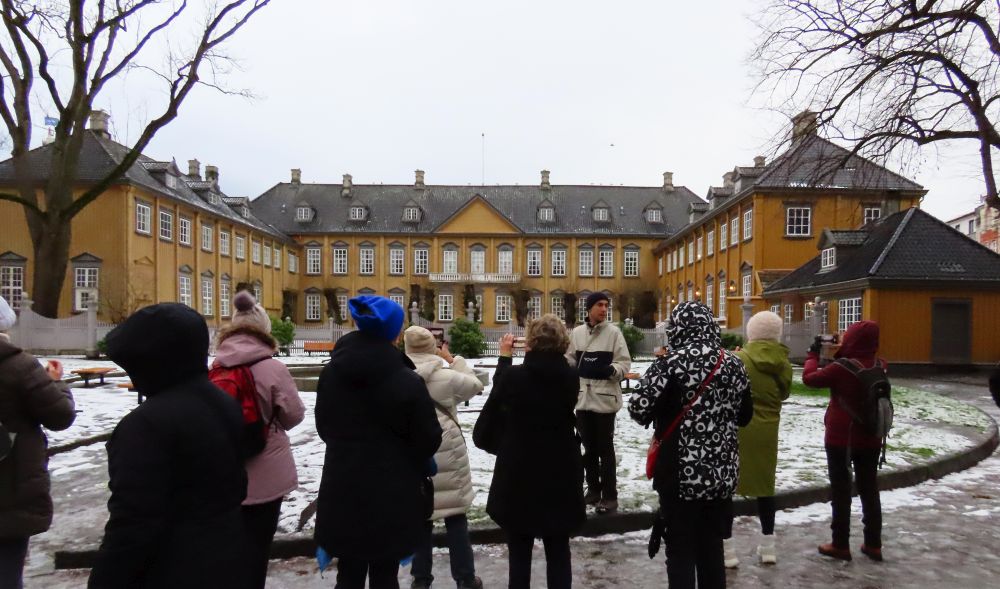 A group of people looking at the palace in Trondheim.