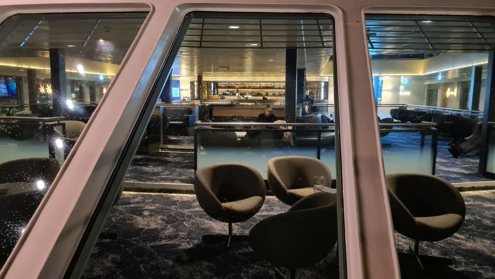 Looking into a large window at a large seating area with chairs and tables in clusters.