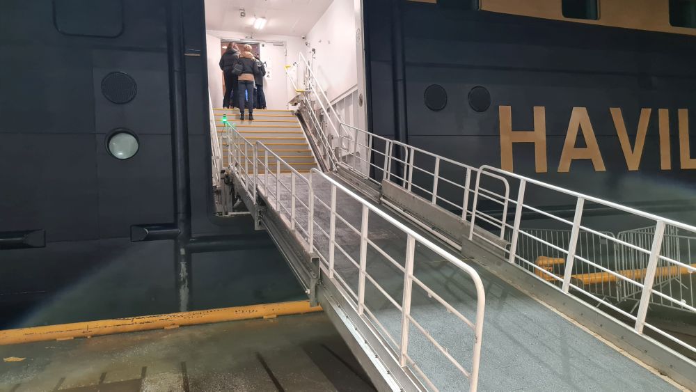 An opening in the side of the ship has a stairway inside it and a long ramp extending outside, with railings along its sides.