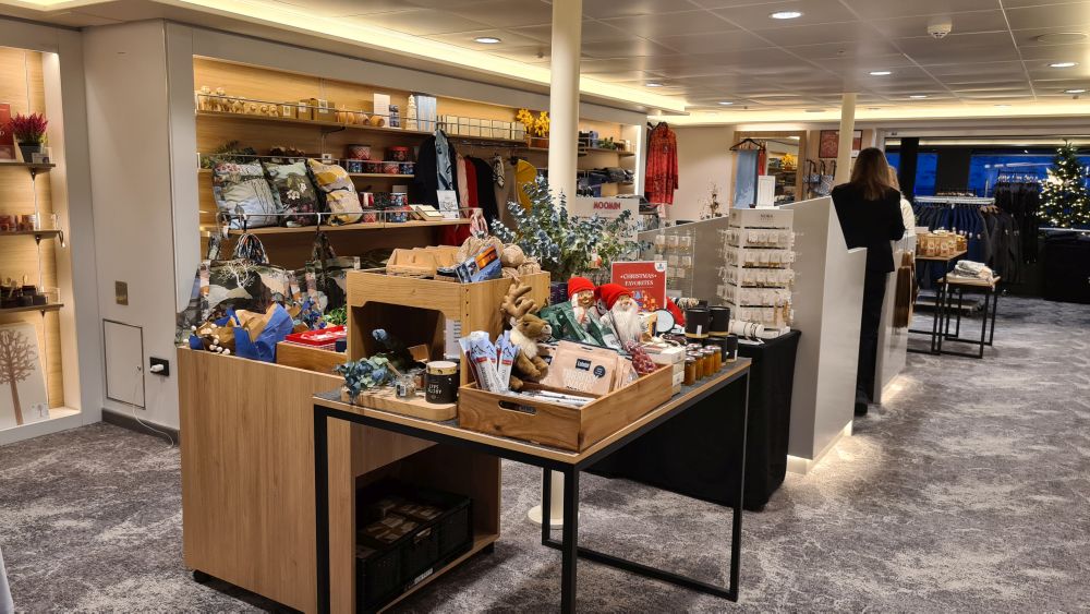 A shop with various items on tables and shelves, racks of jackets at the far end.