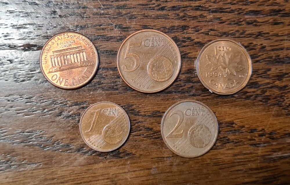 Top, left to right: a US penny, a 5-eurocent coin, a Canadian penny. Bottom, left to right: a 1-eurocent coin and a 2-eurocent coin