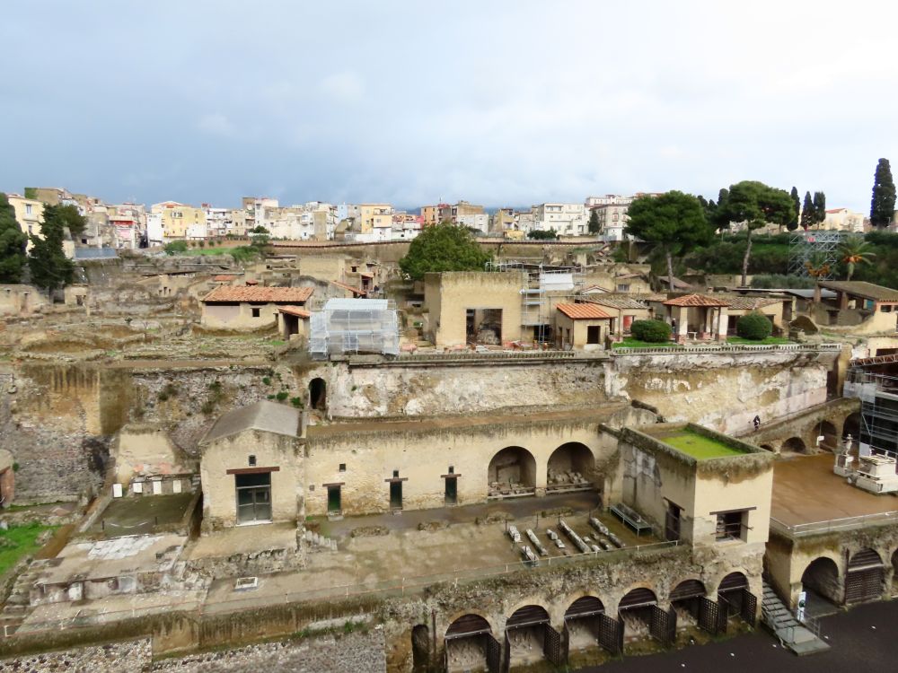 Many stone buildings, some with roofs and some ruins, very tightly packed up a slope.