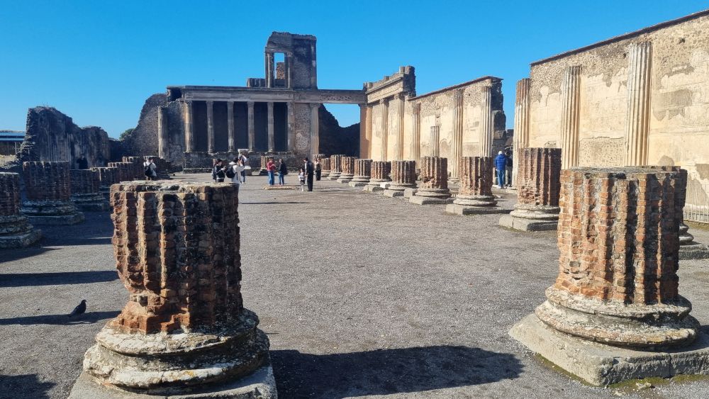 A large plaza with the stubs of columns around the outside, and some taller columns at the far end.