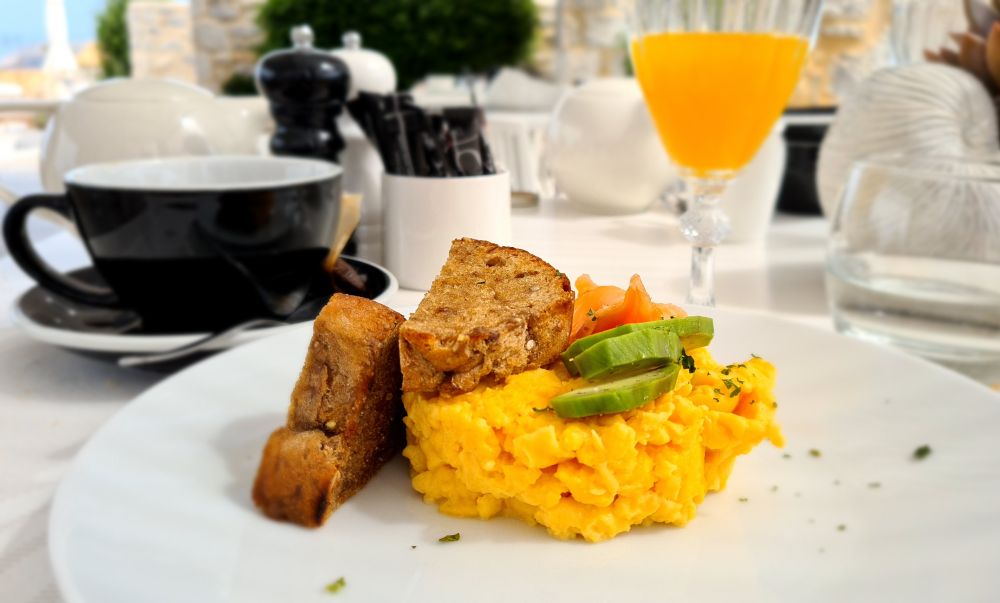 Eggs in a neat circle, two thick slices of brown bread, slices of avocado and salmon on top.