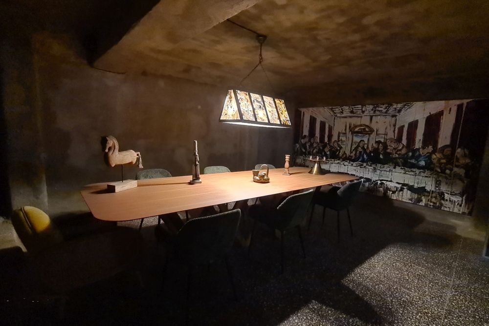 A dark space with a decorative lamp above a long table.