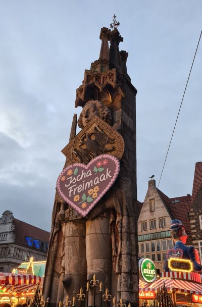 Tall statue of a knight with a heart sign hanging around its neck.